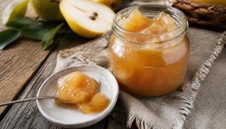 Pot de confiture de poires maison au Confisuc, avec des poires fraîches et une cuillère en bois sur une table en bois rustique