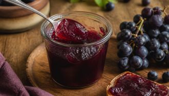 Pots de gelée de raisins noirs maison posés sur un torchon en lin, avec des grappes de raisins noirs frais à côté
